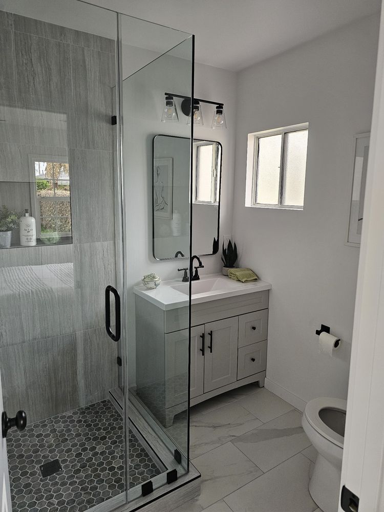Walk-in glass shower with wood-look tile by SummitForge Construction